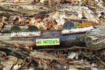 Sign on log saying "Be Patient"