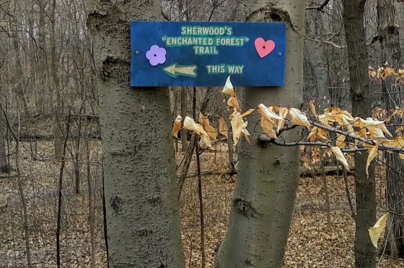 Sign on tree saying "Sherwood's Enchanted Forest Trail this way"